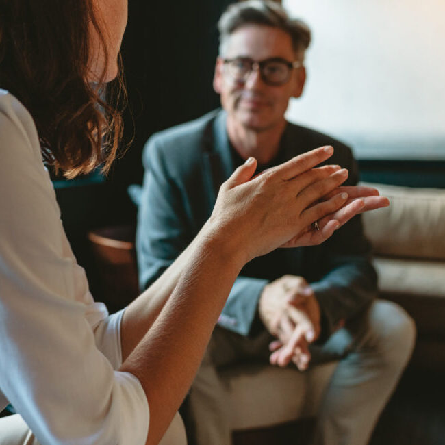 Two business people discussing in office lounge. Businesswoman talking with a male colleague in office lobby.